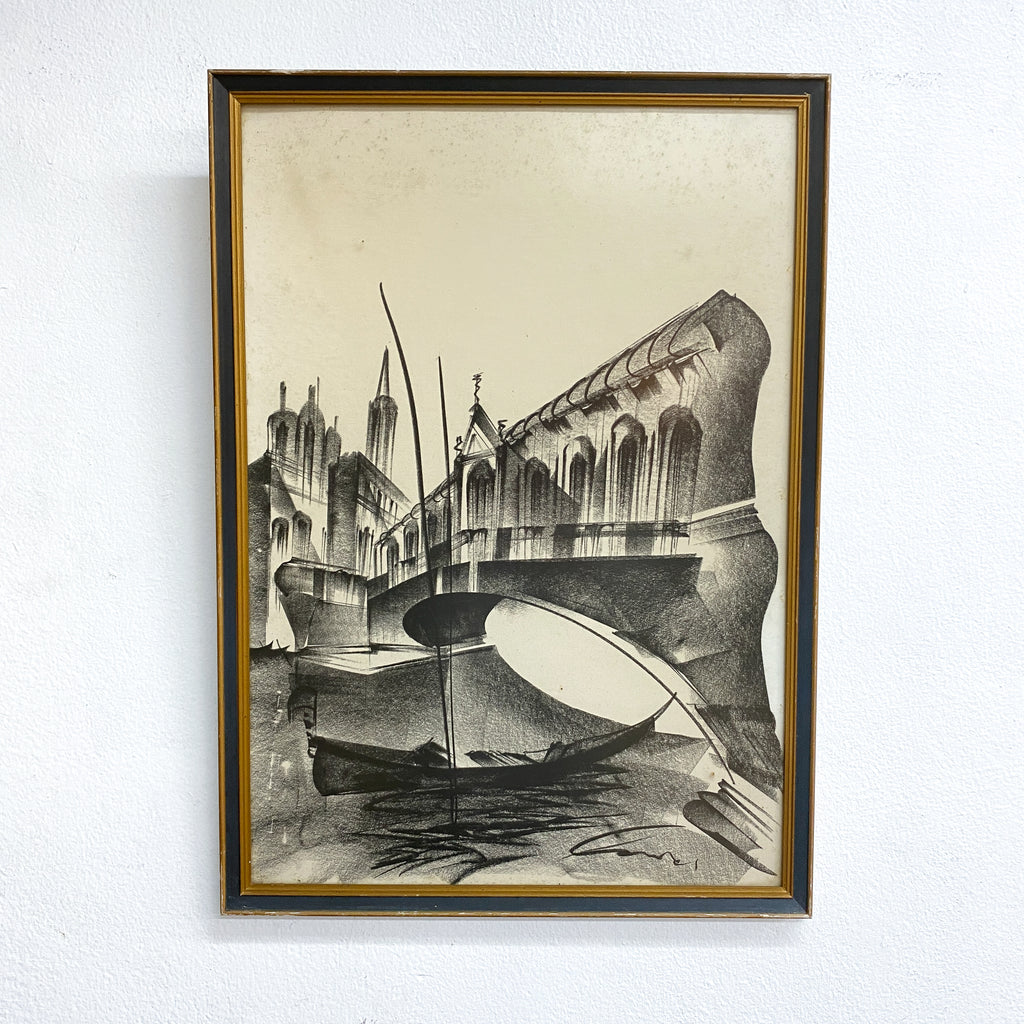 Framed artwork of a cityscape with a boat on water, on a white wall.
