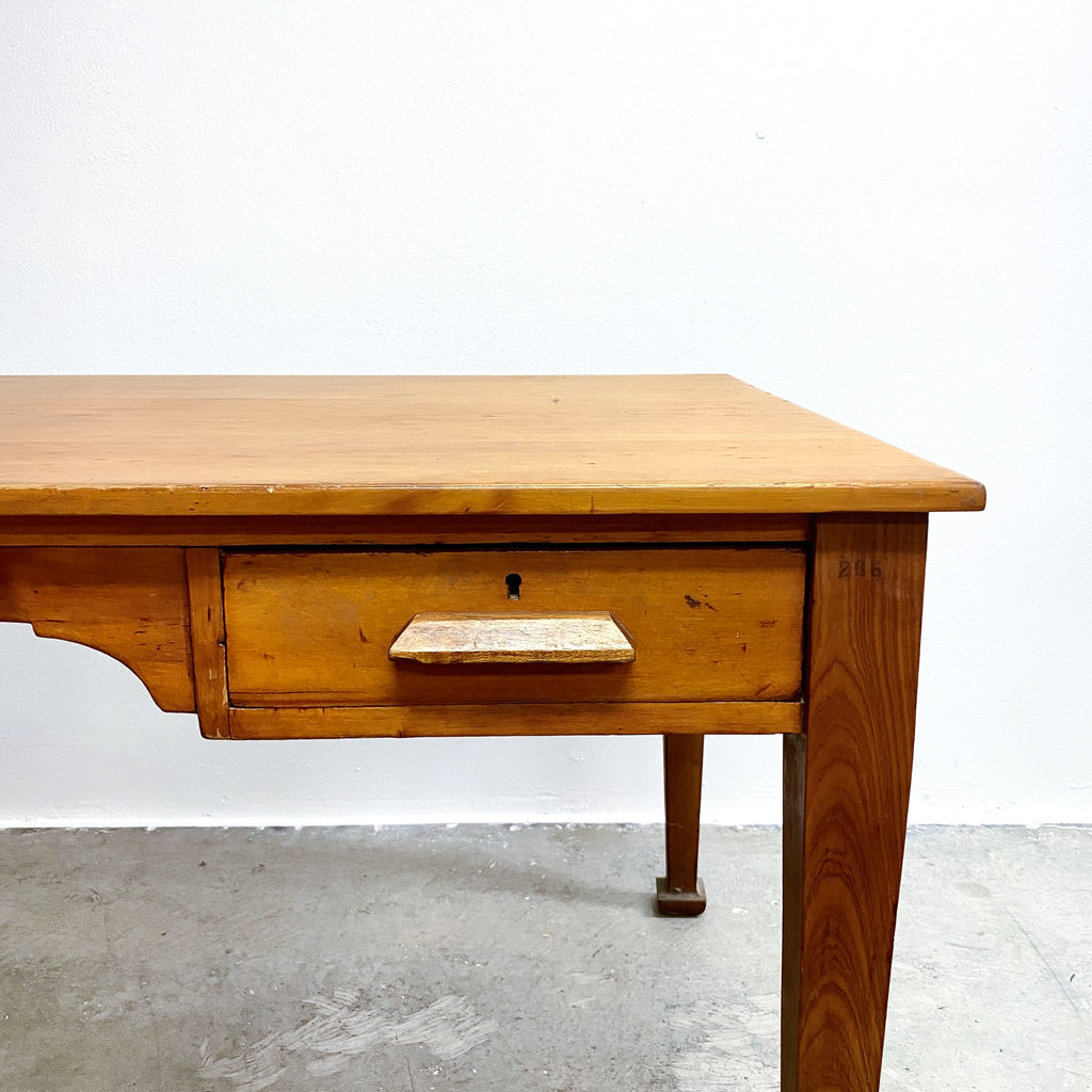 Wooden desk with a single drawer on a plain background