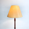Floor lamp with a beige shade and wooden base on a light gray background