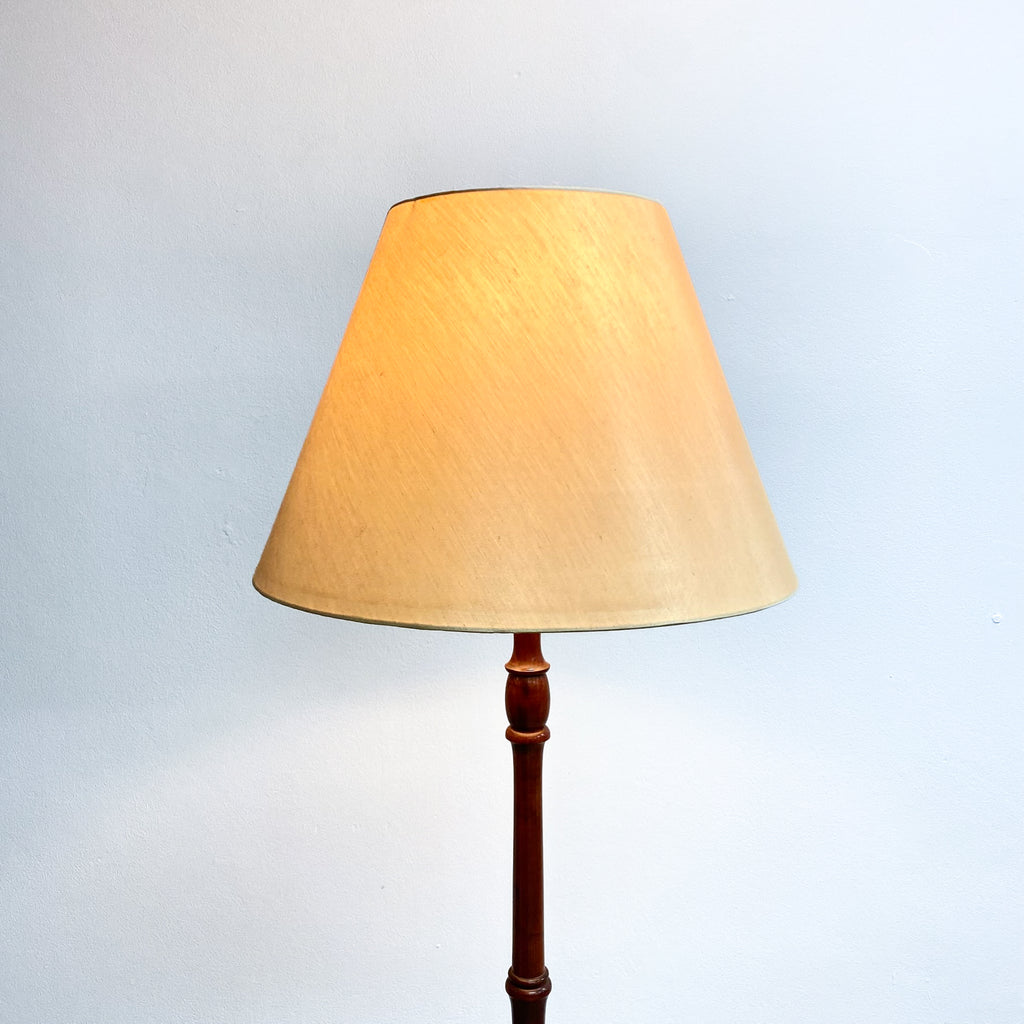 Floor lamp with a beige shade and wooden base on a light gray background