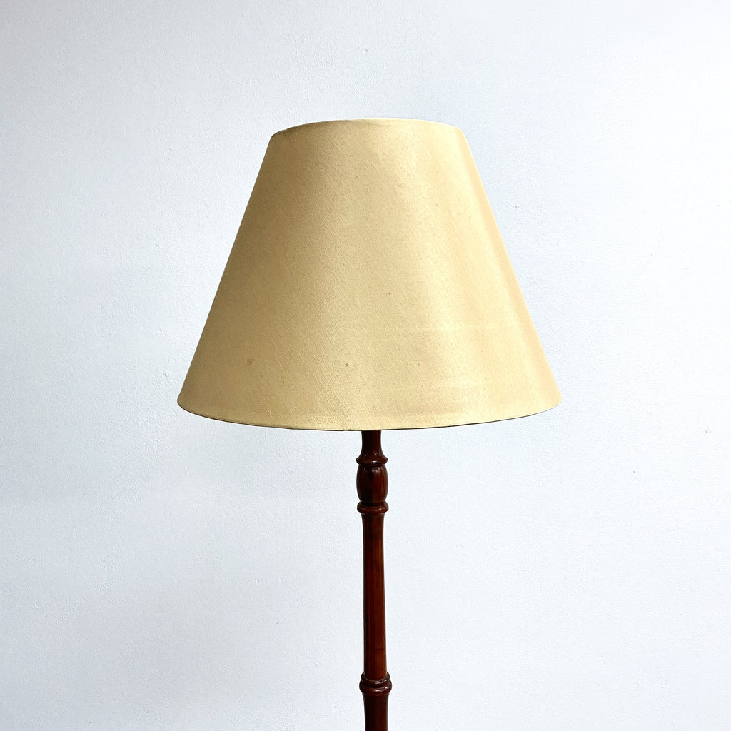 Floor lamp with beige shade and wooden base on a white background