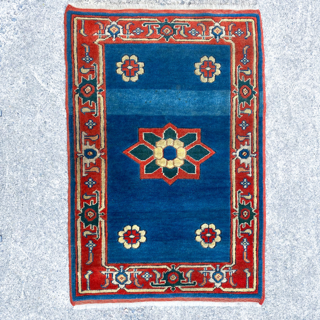 Decorative rug with blue center and red border on a light gray background
