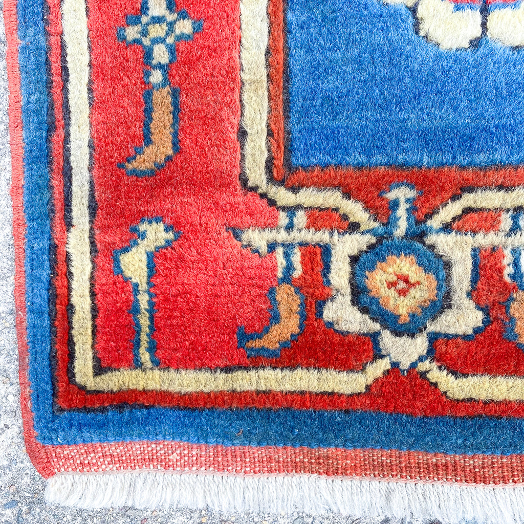 Close-up of a colorful patterned rug with red, blue, and white colors.