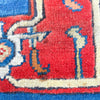Close-up of a colorful patterned rug with red, blue, and beige colors.
