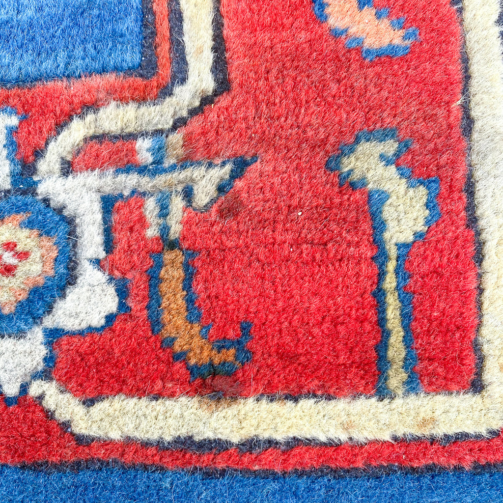 Close-up of a colorful patterned rug with red, blue, and beige colors.