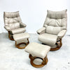 Two beige leather recliner chairs with ottomans on a white background