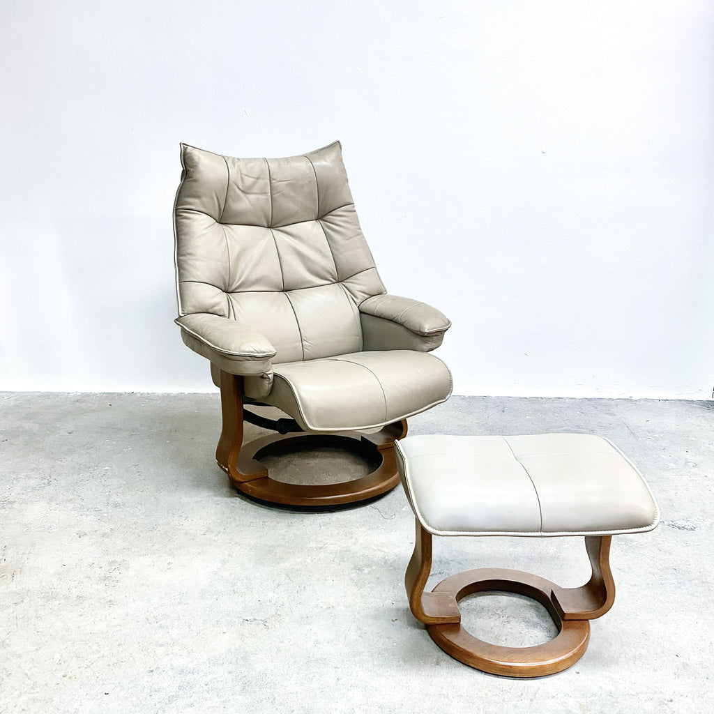 Beige leather recliner chair with ottoman on a light gray floor.