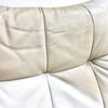 Close-up of beige leather sofa with visible wear and tear on a white background
